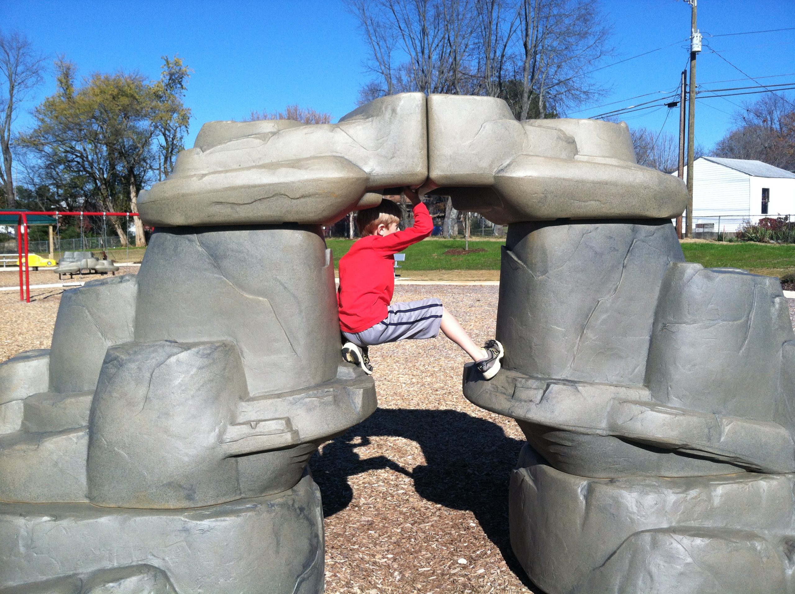 child playing on playground structure that looks like rocks